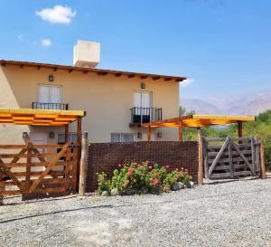 uma casa com uma cerca e flores à frente dela em Malvón em Cafayate