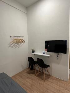 een kamer met een bureau met 2 stoelen en een televisie bij KIWI INN in Taiping