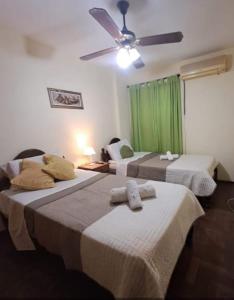 two beds in a room with a ceiling fan at Córdoba Te Espera in Cordoba