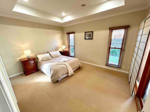 a large bedroom with a bed and two windows at Grand retreat in peaceful street in Wodonga