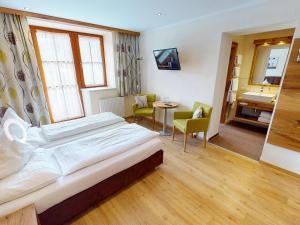 - une chambre avec un grand lit, une table et des chaises dans l'établissement Hotel Gasthof Obermair, à Fieberbrunn