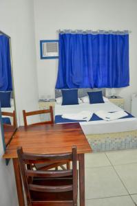 um quarto com uma cama e uma mesa com uma janela azul em Hotel Litoral Norte em Caraguatatuba