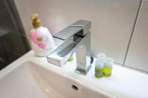 a bathroom sink with a faucet and bottles on it at Cozy Luxury Apartments Maurer Residence #Targu Mures in Târgu-Mureş