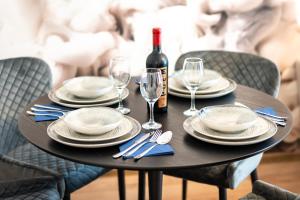 a table with a bottle of wine and plates and glasses at Cozy Luxury Apartments Maurer Residence #Targu Mures in Târgu-Mureş