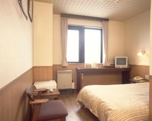 een slaapkamer met een bed, een raam en een bureau bij Hotel Marsh Land in Kushiro