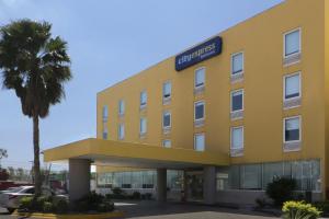 un hôtel jaune avec un palmier devant lui dans l'établissement City Express by Marriott Nuevo Laredo, à Nuevo Laredo