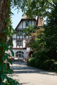 een groot wit huis met zwarte ramen en bomen bij Boutique Hotel Waldhaus beider Basel in Bazel