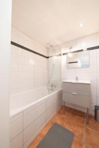 un bagno bianco con vasca e lavandino di Appartement Gardhenn Stadium LCLD Arena Groupama Lyon a Meyzieu