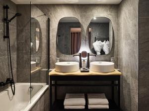 a bathroom with two sinks and a tub and mirrors at Hôtel L'Arboisie in Megève