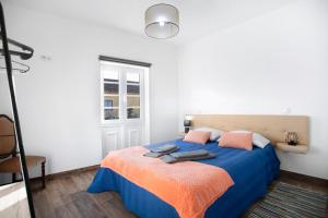 una camera da letto con letto con lenzuola blu e cuscini rosa di Casa da Padaria a Leiria