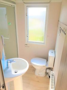 baño con aseo y lavabo y ventana en Sea Break, Perran Sands, Perranporth, en Perranporth