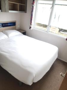 Cama blanca en habitación con ventana en Sea Break, Perran Sands, Perranporth, en Perranporth