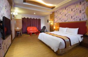 a hotel room with a large bed and a chair at Summer House Motel in Tainan