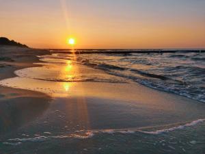 einen Sonnenuntergang am Strand mit dem Meer in der Unterkunft Strandhäuser Blankenfohrt in Ückeritz