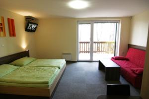 a bedroom with a bed and a red couch at Penzión NADKA in Bojnice