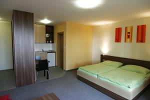 a bedroom with a bed and a small kitchen at Penzión NADKA in Bojnice