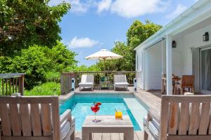 een zwembad met stoelen en een tafel en een parasol bij Hotel Le Toiny in Gustavia