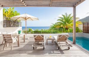 een patio met een tafel en stoelen en een zwembad bij Hotel Le Toiny in Gustavia