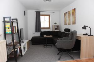 a living room with a black couch and a desk at Haus Blumenampel in Schmalkalden