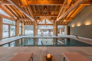 een binnenzwembad in een huis met houten plafonds bij Chalet Eden Eco Hotel, Restaurant & Wellness in La Thuile