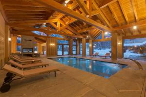 een binnenzwembad in een huis met houten plafonds bij Chalet Eden Eco Hotel, Restaurant & Wellness in La Thuile