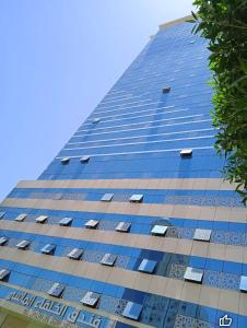 a tall blue building with windows on the side at فندق الخلفاء الماسي in Makkah