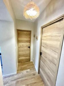 un couloir avec une porte en bois et un lustre dans l'établissement Cosy ANELA, à Saint-Claude