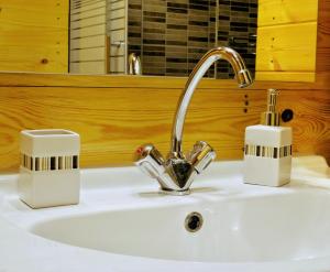 a bathroom sink with a faucet and two tooth brushes at Kadosa Jurta Apartman in Esztergom