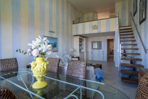 uma sala de estar com uma mesa de vidro com um vaso de flores em Miramare apartments em Punta Ala