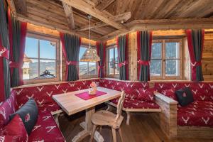 una sala da pranzo con divano rosso e tavolo di Chalets Almdorf Haidenberg a Brunico