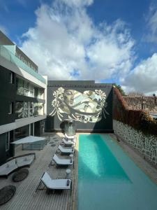 una piscina con tumbonas y un mural en un edificio en Ilum Experience Home, en Buenos Aires