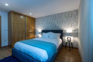 a bedroom with a large bed with a blue blanket at Live in Aveiro in Aveiro