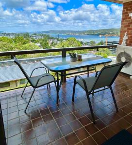 eine Terrasse mit einem Tisch und Stühlen auf dem Balkon in der Unterkunft Gosfords Best Location with Views in Gosford