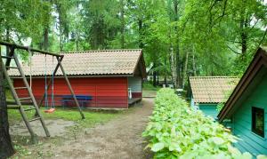 uma casa vermelha e azul com um parque infantil em frente em Waldidylle - Bungalows an der Talsperre Kriebstein em Kriebstein