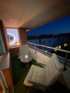 a balcony with two chairs and a table on a building at Appartement 59m2 professionnel ou familial Saint Quentin en Yvelines in Montigny-le-Bretonneux