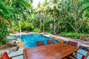 einen Holztisch und Stühle neben einem Pool in der Unterkunft Poinciana 105 in Hamilton Island