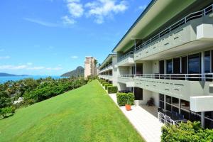 einen Blick nach außen auf ein Gebäude mit grünem Rasen in der Unterkunft Poinciana 105 in Hamilton Island