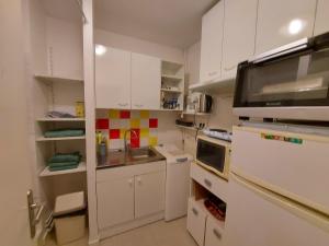 - une petite cuisine avec des placards blancs et un four micro-ondes dans l'établissement Appartement Rennes stade parking gratuit, à Rennes