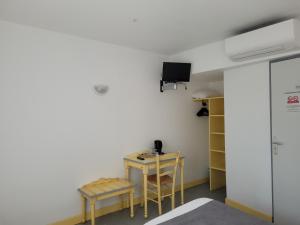 um quarto com uma mesa e duas cadeiras e uma televisão em Hotel Le Vanséen em Les Vans