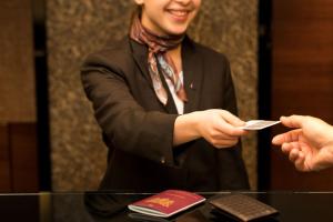 een man in een pak die een persoon een stuk papier geeft bij Sheraton Brussels Airport Hotel in Zaventem