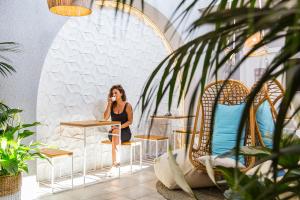 a woman sitting at a table talking on a cell phone at CapoBlu Hotel in Pula