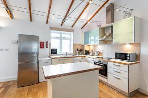 a large kitchen with white cabinets and stainless steel appliances at Light and airy upside down house in Hackney in London