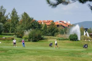 Pirin Golf Mountain View Retreat في رازلوغ: مجموعة من الناس يلعبون الغولف على ملعب للجولف