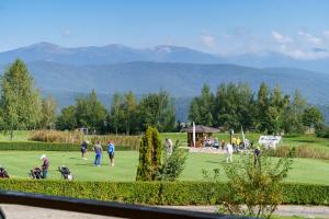 Pirin Golf Mountain View Retreat في رازلوغ: مجموعة من الناس يلعبون الغولف على ملعب للجولف