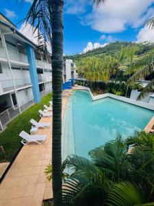 a resort pool with chairs and a palm tree at at Marina Shores in Airlie Beach