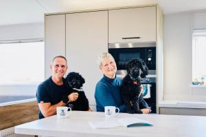 dos hombres sentados en una mesa con dos perros en C-Scape Lodge, en Newquay