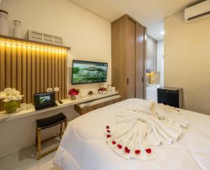 - une chambre avec un grand lit blanc et une télévision dans l'établissement Verdant Bali Sekar Sari, à Denpasar