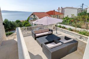 um pátio com uma mesa, um guarda-sol e cadeiras em Luxury apt w pool 3 balconies terrace & sea view em Omiš