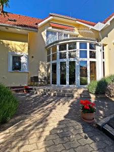 a house with a patio and a porch with red flowers at Hotel Penta Lux in Tata