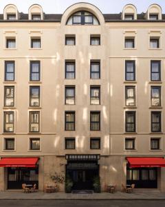 un edificio de apartamentos con mesas delante en Hôtel Des Grands Voyageurs, en París